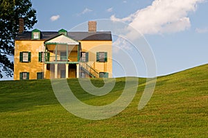 Yellow house on grassy hill photo