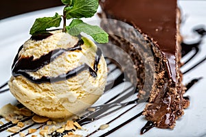 Yellow ice cream ball with chocolate topping and slice of chocolate cake. Forming a gourmet dessert