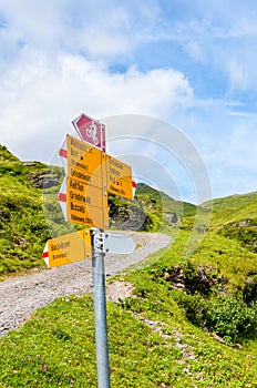 Yellow information sign on the path from Grindelwald leading to Bachalpsee lake in Switzerland. Tourist sign giving directions to