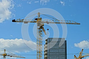 Yellow iron tower crane over a gray unfinished house against