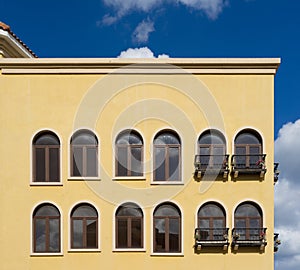 Yellow Italian style building with windows and blue sky