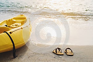 Yellow kayak and flip flop on the beach in sunset, summer time vacation holidays concepts, vintage tone soft focus