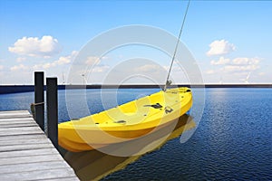 A yellow kayak tied to a wooden bridge after fishing on the lake