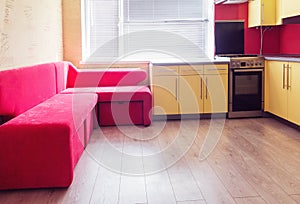 yellow kitchen with cupboards, window, laminate and red soft couch