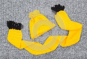 Yellow knitted hat and scarf on gray wool background