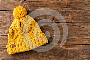 Yellow knitted hat on wooden background with copyspace.