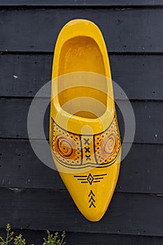 Yellow large Dutch traditional wooden shoe on the black wall in The Netherlands