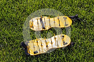 Yellow lawn aerator sandals with nails for lawn cultivation.