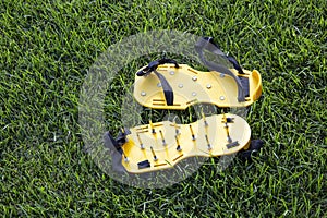 Yellow lawn aerator sandals with nails for lawn cultivation.