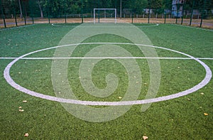 Yellow leaves on artificial green grass on football field. Green artificial turf grass soccer sports field with white stripe line