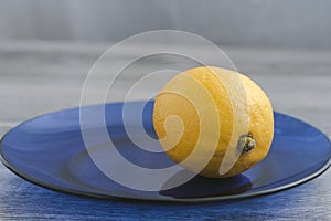 Yellow lemon on a blue glass plate