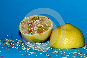 yellow lemon cut in half on a blue background with decorative sugar