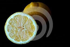 Yellow lemon cut in half close up on a black background.