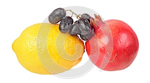 Yellow lemon, red pomegranate and dark purple ripe grapes isolated on white background. Ingredients for salad