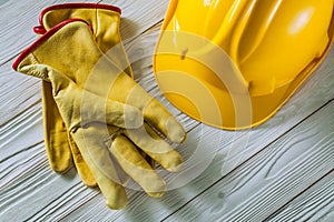 Yellow lether working gloves and construction helmet on vintage white painted wooden boards