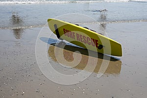 Yellow lifeguard surf rescue surf board by the ocean on the sand