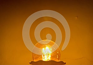 Yellow light bulb lit in the dark close up view