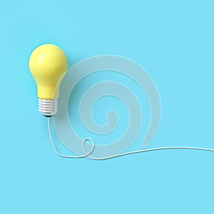 Yellow light bulb with wire on blue background for copy space