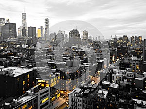 Yellow lights glowing in black and white cityscape of the Manhattan skyline in New York City at night