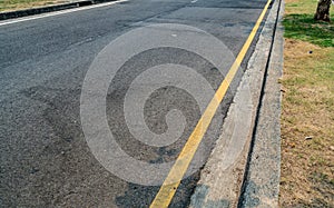 Yellow line on asphalt road with concrete curb