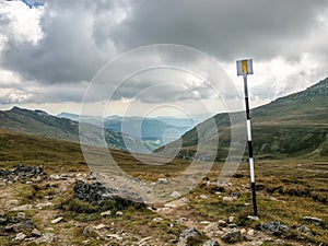 Yellow line hiking trail mark painted on a metal pole in the Bucegi Mountains, Romania