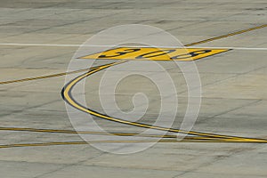 Yellow lines markings for aircraft movement with parking numbers on the apron at the airport.