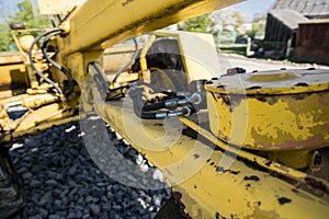 Yellow loader with empty bucket stands on a stone gravel during road construction works. The stones for the road