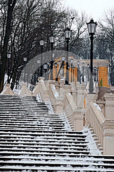 Yellow long staircase with vintage lanterns at winter. They connect Column of Magdeburg Law with Volodimirsky descent uzvoz
