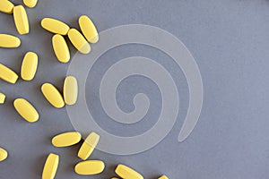 Yellow long vitamins or pills on gray background, close-up, copy space. Nutritional supplements concept, health, vitamins, trendy