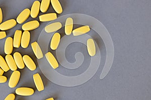 Yellow long vitamins or pills on a gray background, closeup, mock up, copy space. Nutritional supplements concept, health,
