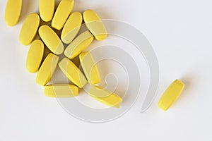 Yellow long vitamins or pills on white background, macro, close-up, copy space, flatly. Nutritional supplements concept, health,