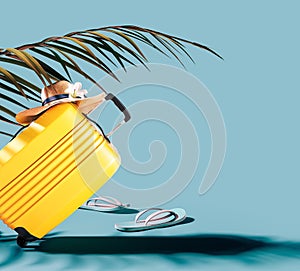 Yellow luggage bag with hat and palm leaf on blue background with copy space.