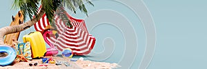Yellow luggage with summer beach accessories and umbrella under the palm tree. Summer travel concept background with copy space.