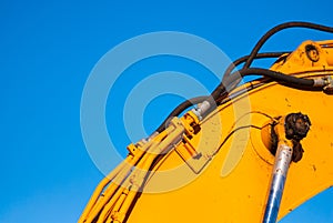 Yellow machinery and hydraulics on blue sky.
