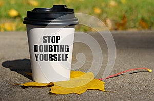 On a yellow maple leaf there is a cup of coffee on which is written - Stop doubting yourself