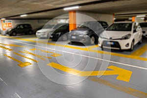 Yellow markings with blurred modern cars parked inside closed underground parking lot