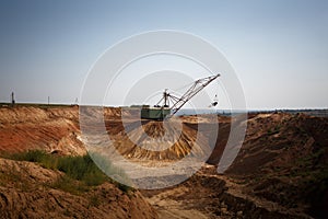 Yellow massive metal mobile crane on a blue sky background. An industrial moving machine in the foundation pit. Copy