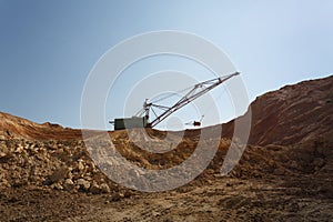 Yellow massive metal mobile crane on a blue sky background. An industrial moving machine in the foundation pit. Copy