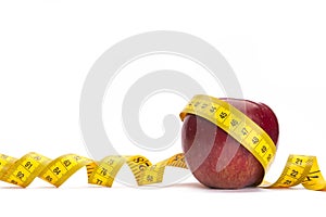 Yellow measure tape around a red apple as a weight loss concept