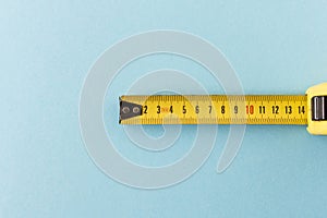 Yellow measuring tape on a blue background. Close-up