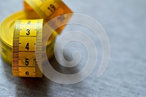 Yellow measuring tape lies on a gray knitted fabric