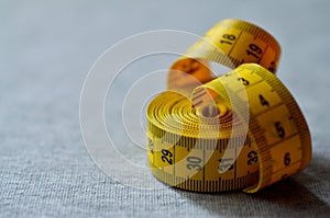 Yellow measuring tape lies on a gray knitted fabric