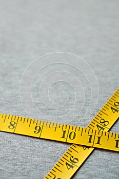 Yellow measuring tape lies on a gray knitted fabric