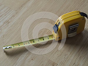 Yellow measuring tape measure showing ten centimetres on wooden photo