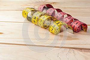 Yellow measuring tape on wooden background. Measuring tape for fitness or tailor work . Close-up