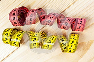 Yellow measuring tape on wooden background. Measuring tape for fitness or tailor work . Close-up