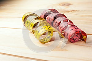 Yellow measuring tape on wooden background. Measuring tape for fitness or tailor work . Close-up