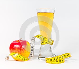 A yellow measuring tape wrapping red apple and juice