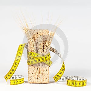 A yellow measuring tape wrapping wheat cracker or crispbread