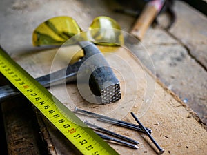 Yellow measurment tape, hammer, nails, protection eyeglass photo